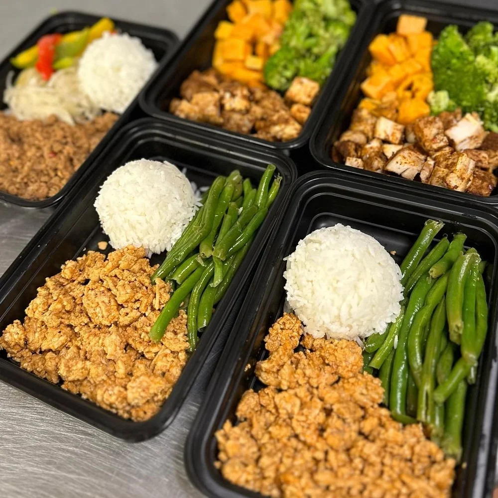 A spread of custom meal-prep trays with chicken, rice and vegetables