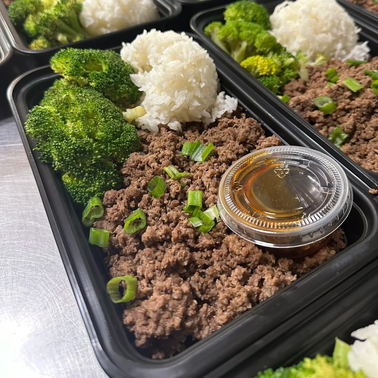 Asian ground beef bowl with broccoli, white rice and scallions in a meal-prep tray